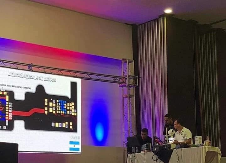 Agustín Scorza durante su primera ponencia internacional en Toluca, México, 2018: trabajo con microscopio frente al público y la medición proyectada en pantalla